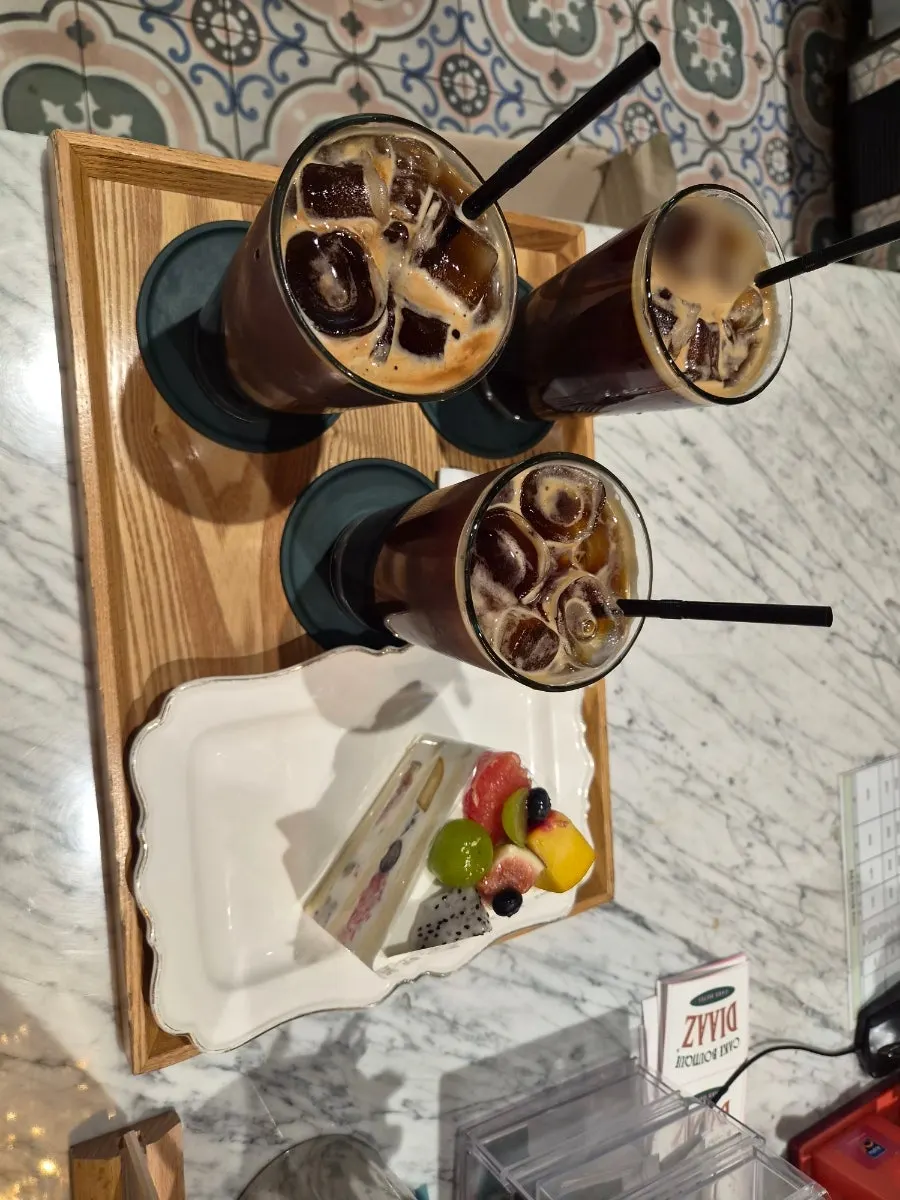 Table setting with 3 iced americanos and a slice of cake