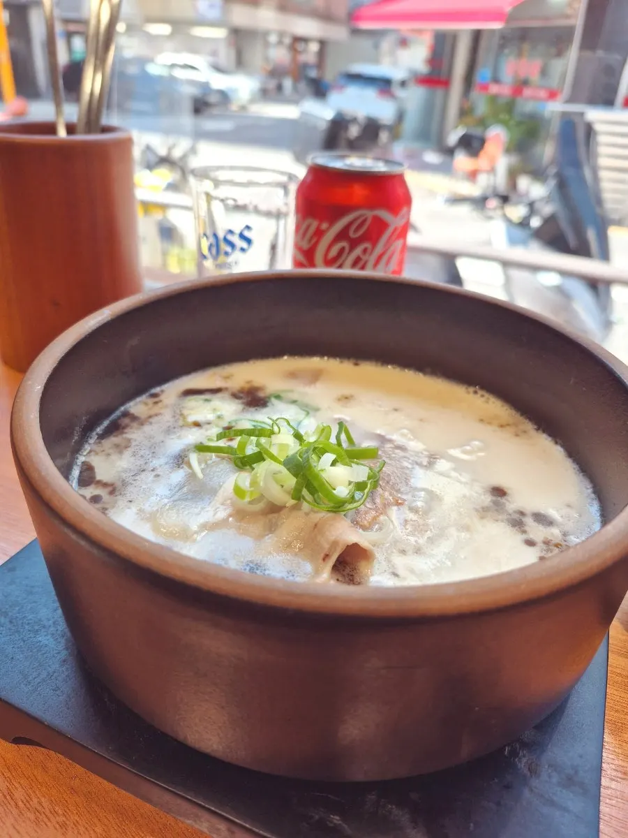 A spoonful of gomtang broth lifted from the bowl