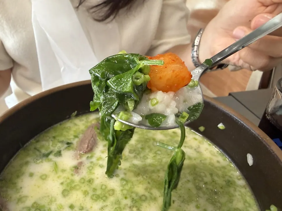 Gomtang with rice mixed in, scooped up together with minari