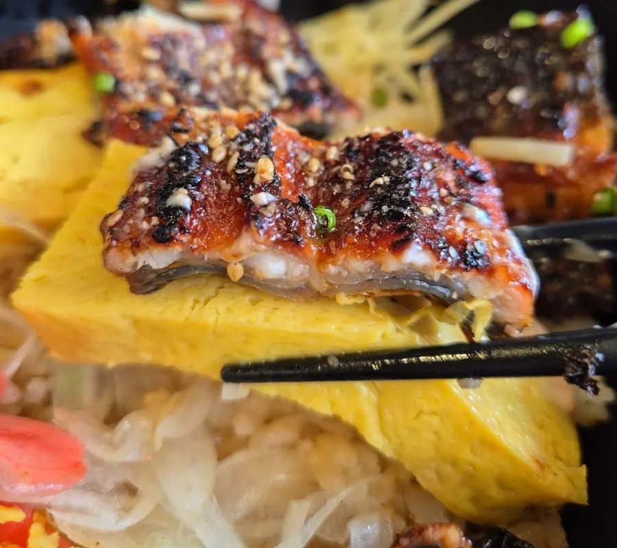 A spoonful taken from the egg-and-eel rice bowl