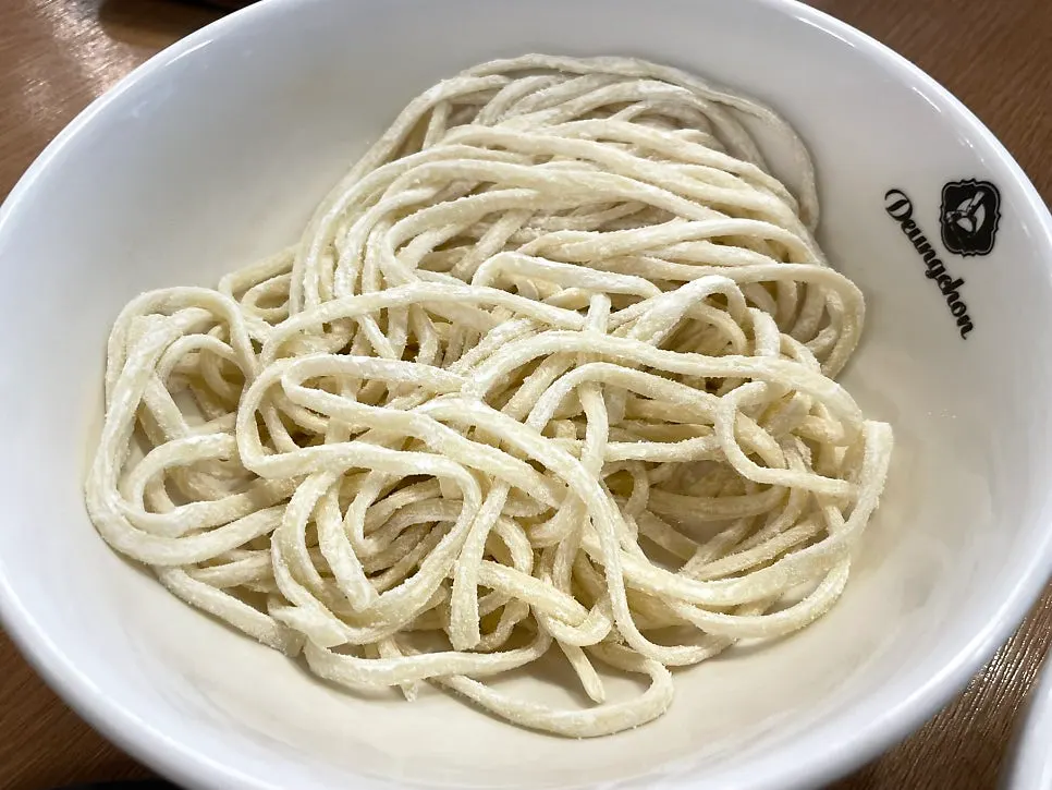 Table setting served with fresh kalguksu noodles and fried rice ingredients together