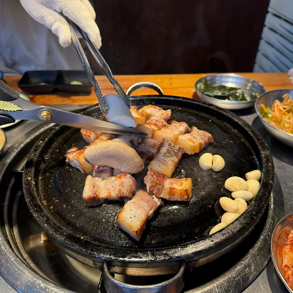 불판 위에서 마무리로 구워지는 두툼한 삼겹살