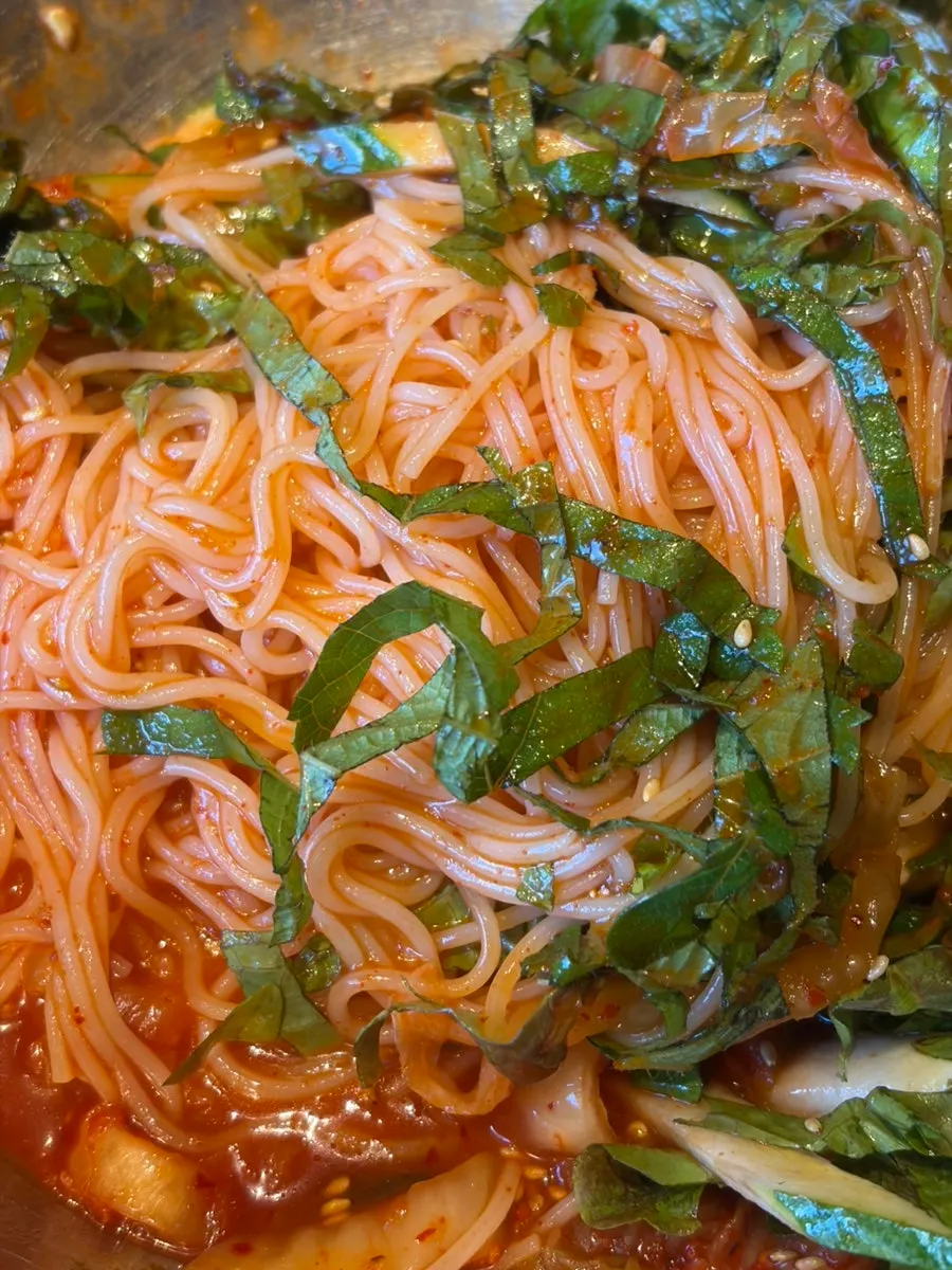 Bibim guksu topped with kimchi, perilla leaves, and boiled egg