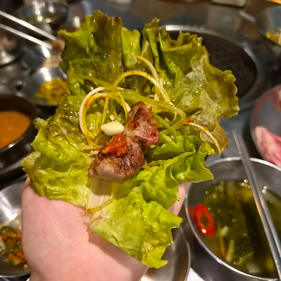 Meat wrapped in fresh lettuce with scallion salad on top