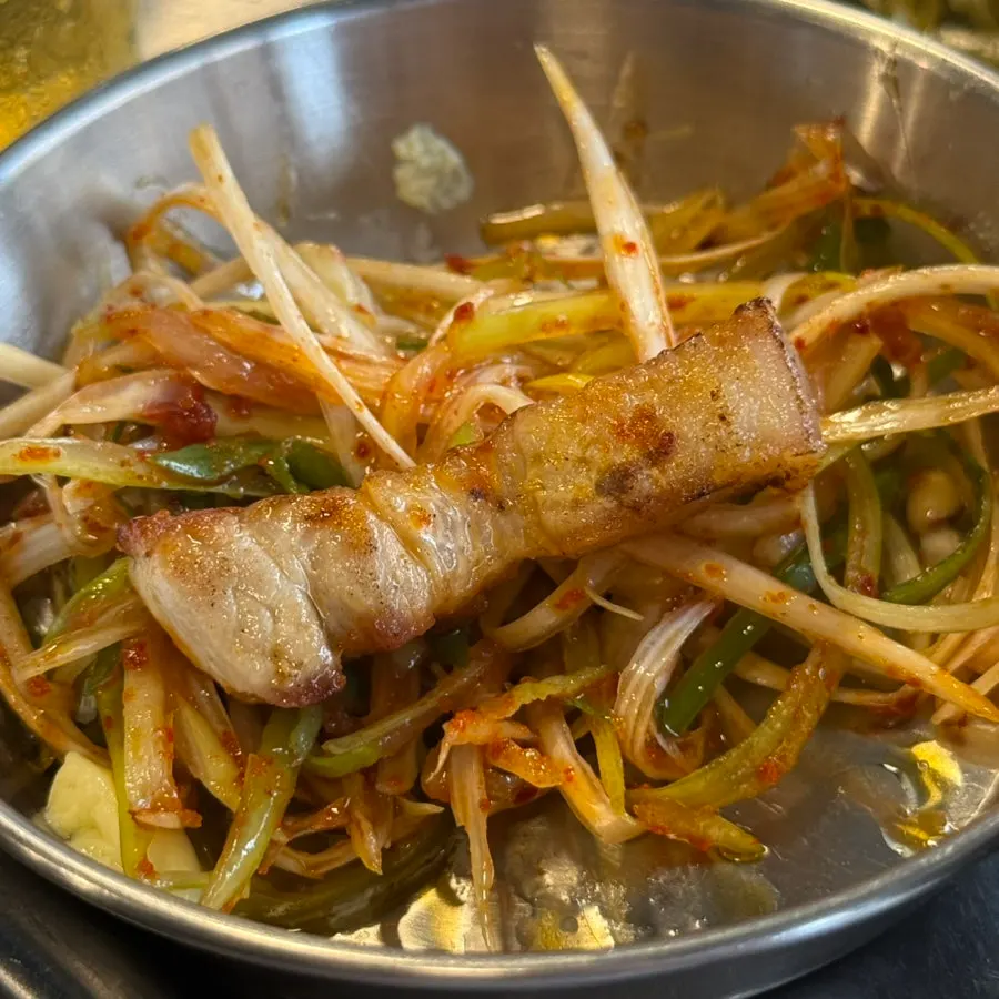Pork belly topped with shredded scallions and grilled kimchi