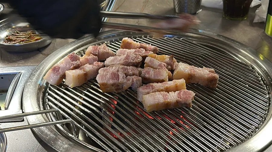 Wide shot of pork belly on the grill