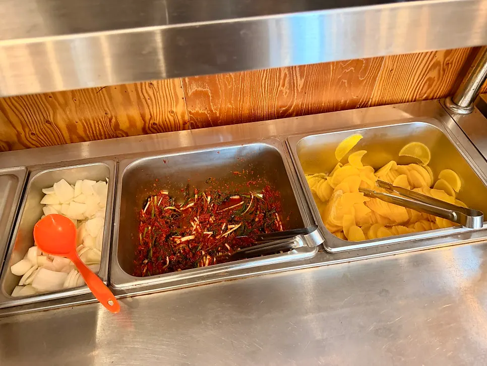 Self-serve corner with green onion kimchi, onion and pickled radish