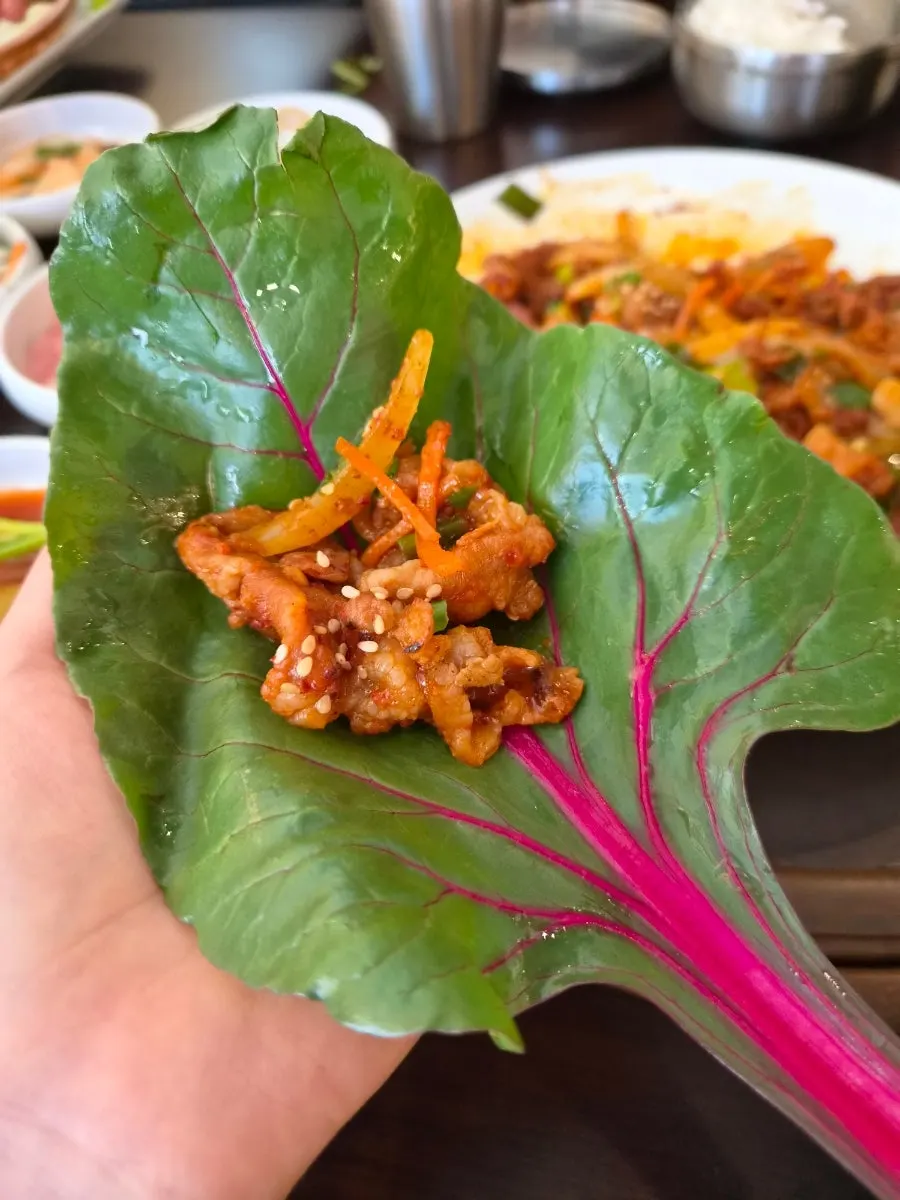 제육볶음과 쌈채소를 함께 싸 먹는 모습
