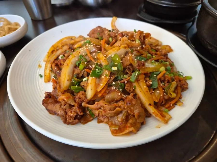 여러 종류 쌈채소와 제육볶음이 놓인 식탁