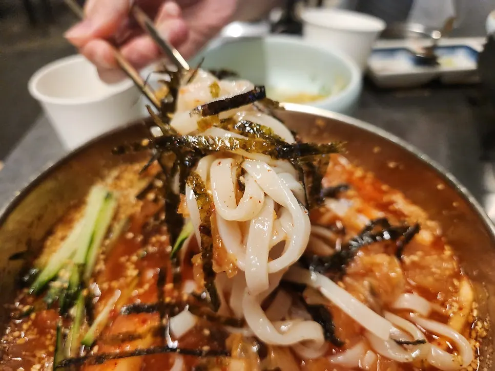Cold kimchi kalguksu topped with cucumber and seaweed flakes