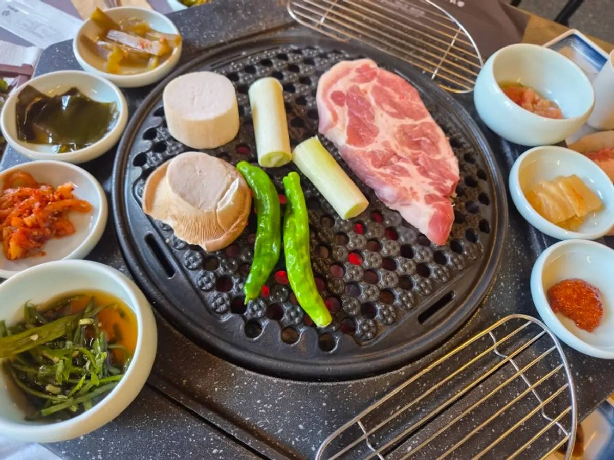 Meat, king oyster mushroom, green onion, and shishito peppers on the grill