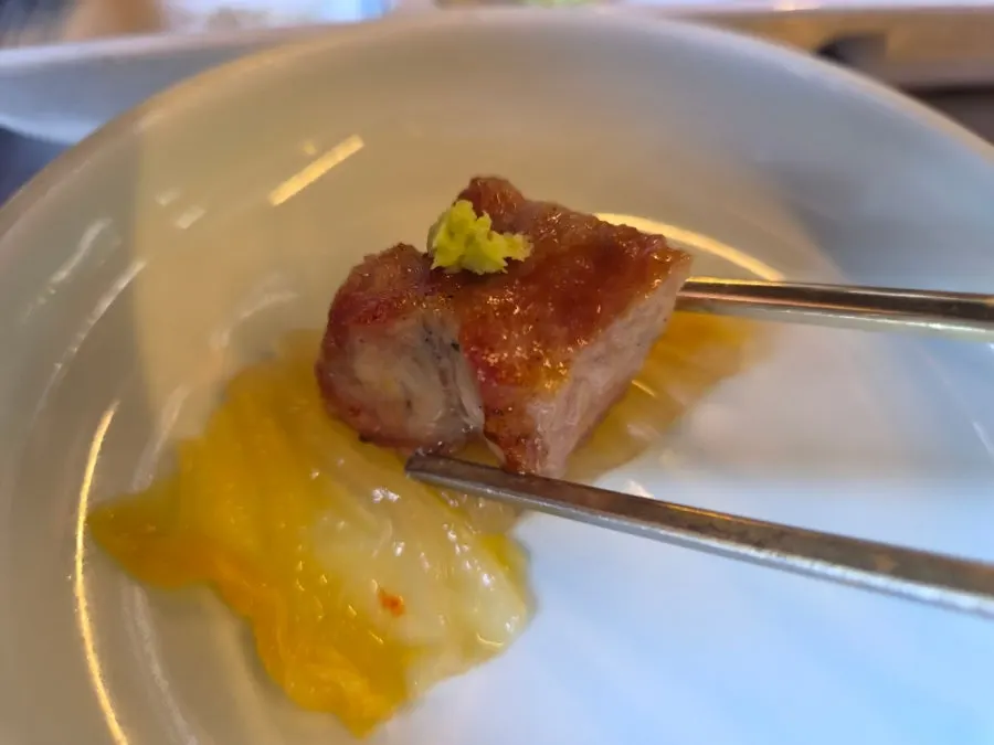 A bite of pork shoulder with wasabi on aged kimchi