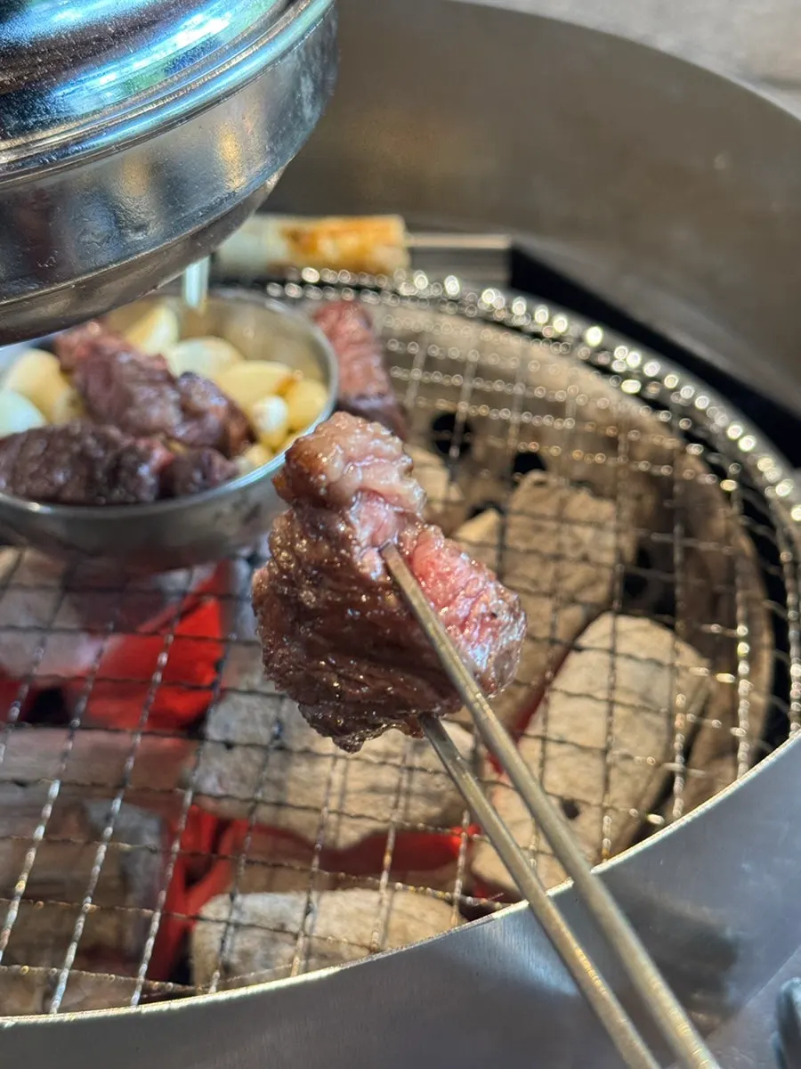 A piece of kkotdeungsim cooking on the charcoal grill
