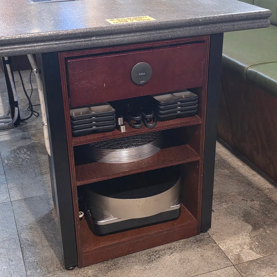 Small plates, tongs, scissors, and a spare grill plate beside the table