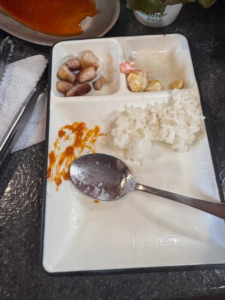 뚜껑을 연 공기밥과 고기 한 점