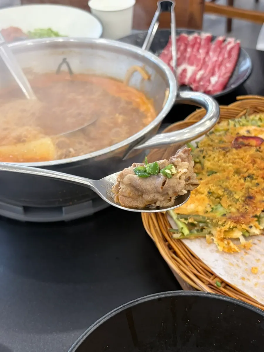 A chopstick-full of noodles in spicy broth
