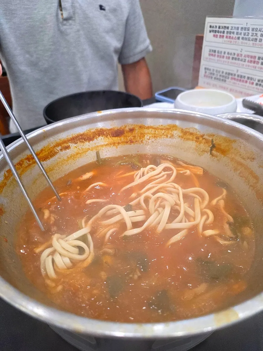 Kalguksu de caldo rojo servido en cuenco