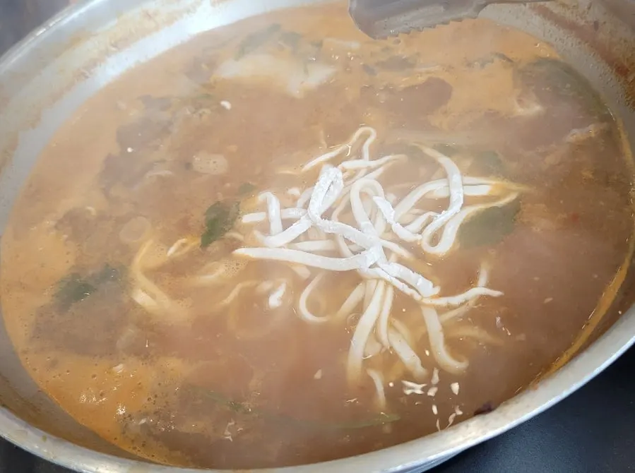 Kalguksu noodles boiling in the red broth