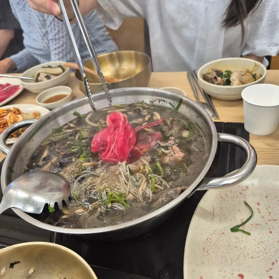 가운데 냄비를 두고 함께 먹는 가족 식탁
