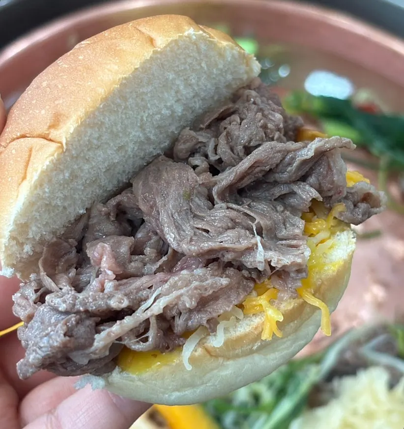 Self-made bulgogi burger with shredded cheese on a morning roll