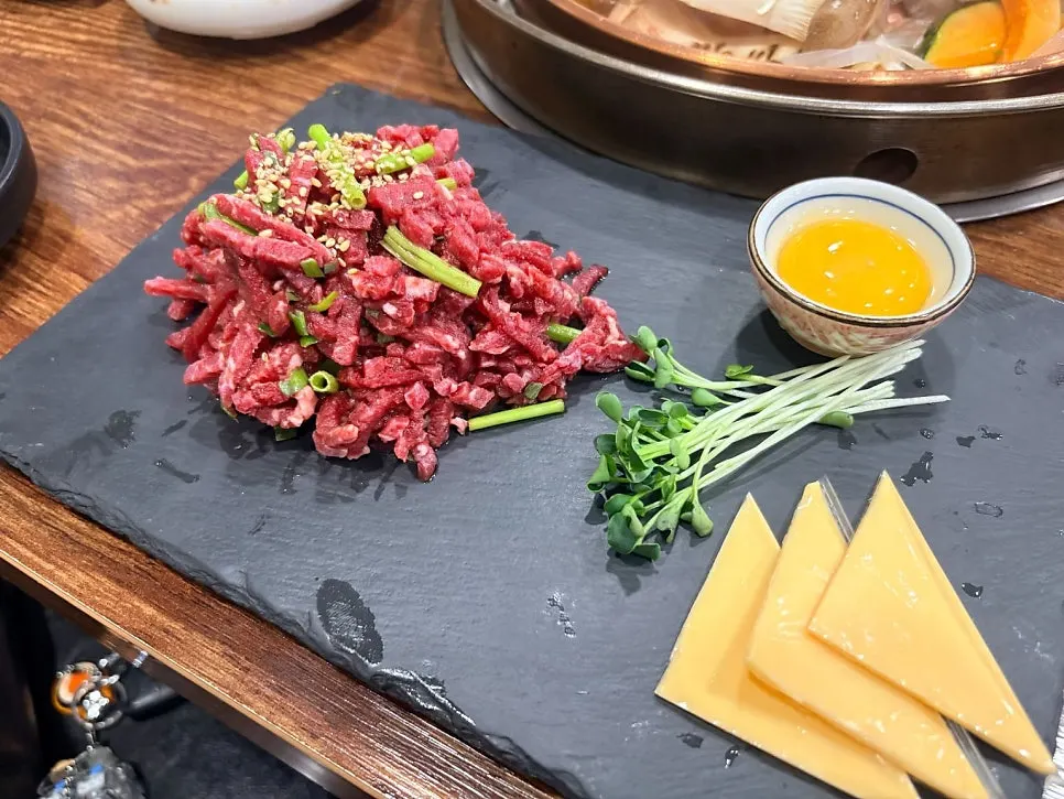 돌판에 담긴 한우 미나리 육회와 노른자