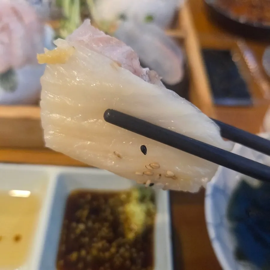 A piece of raw fish dipped in soy sauce with wasabi