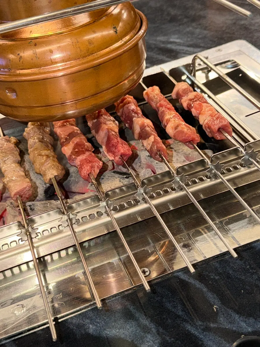 Automatically rotating charcoal grill cooking the lamb skewers