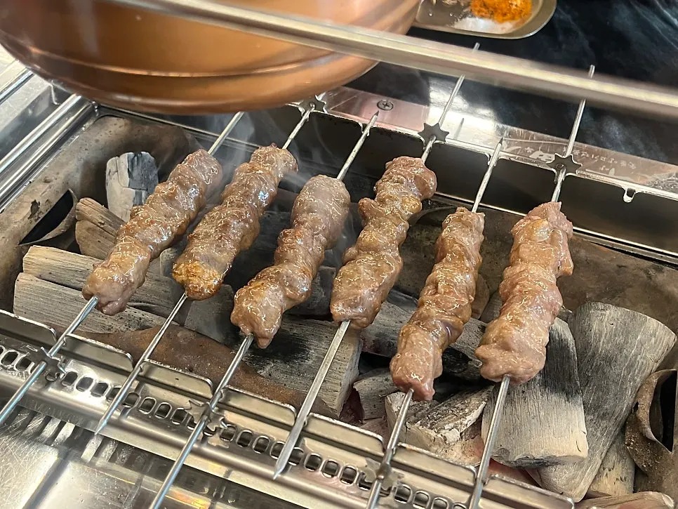 Big lamb skewers grilling over charcoal