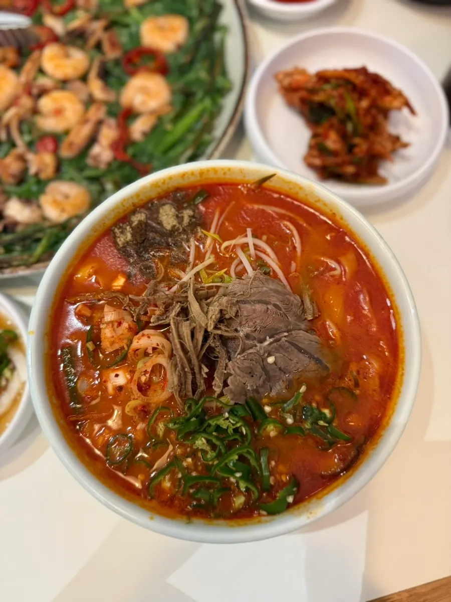 Bowl of yukgaejang kalguksu with bright red broth