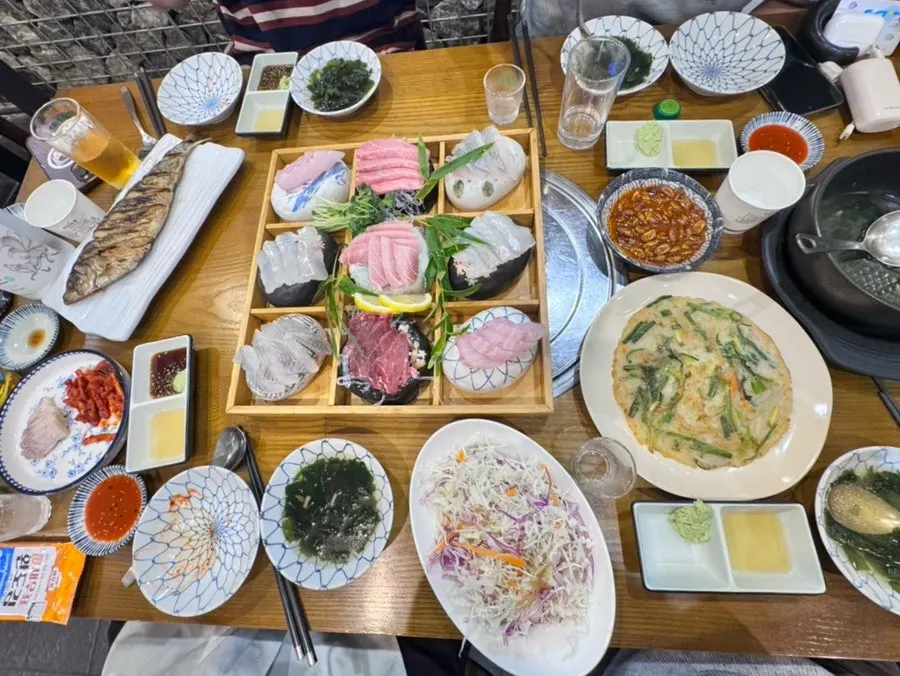 Full view of the table loaded with sashimi and side dishes