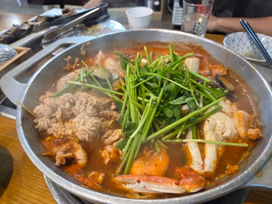 煮えている海鮮鍋と刺身の皿