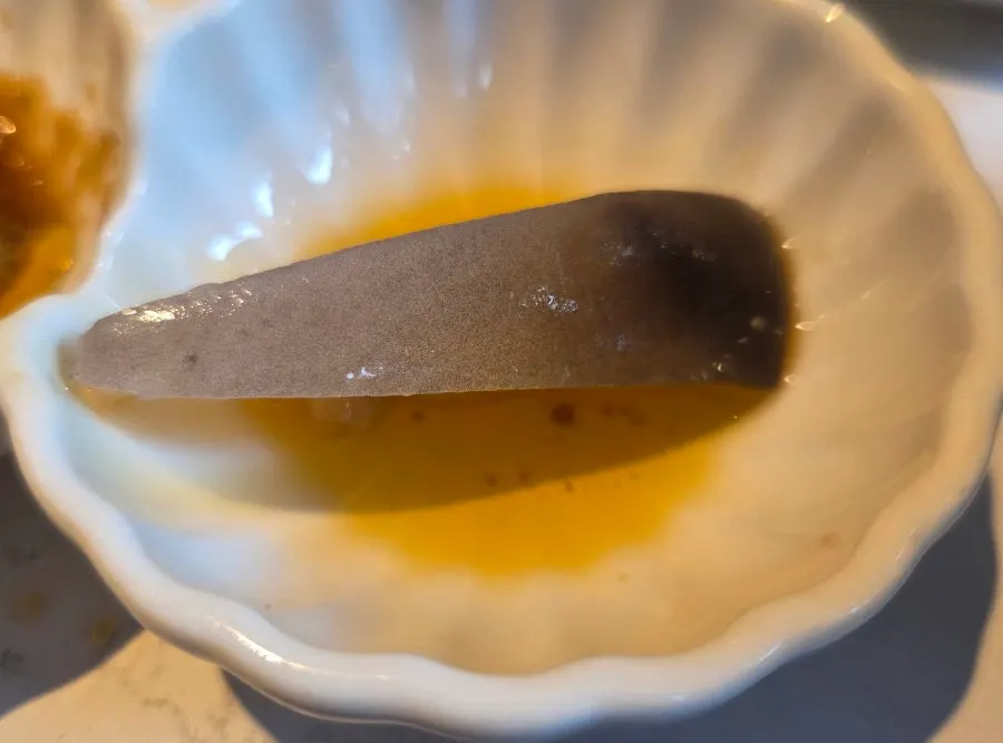 A single piece of tuna lip sashimi placed on the plate