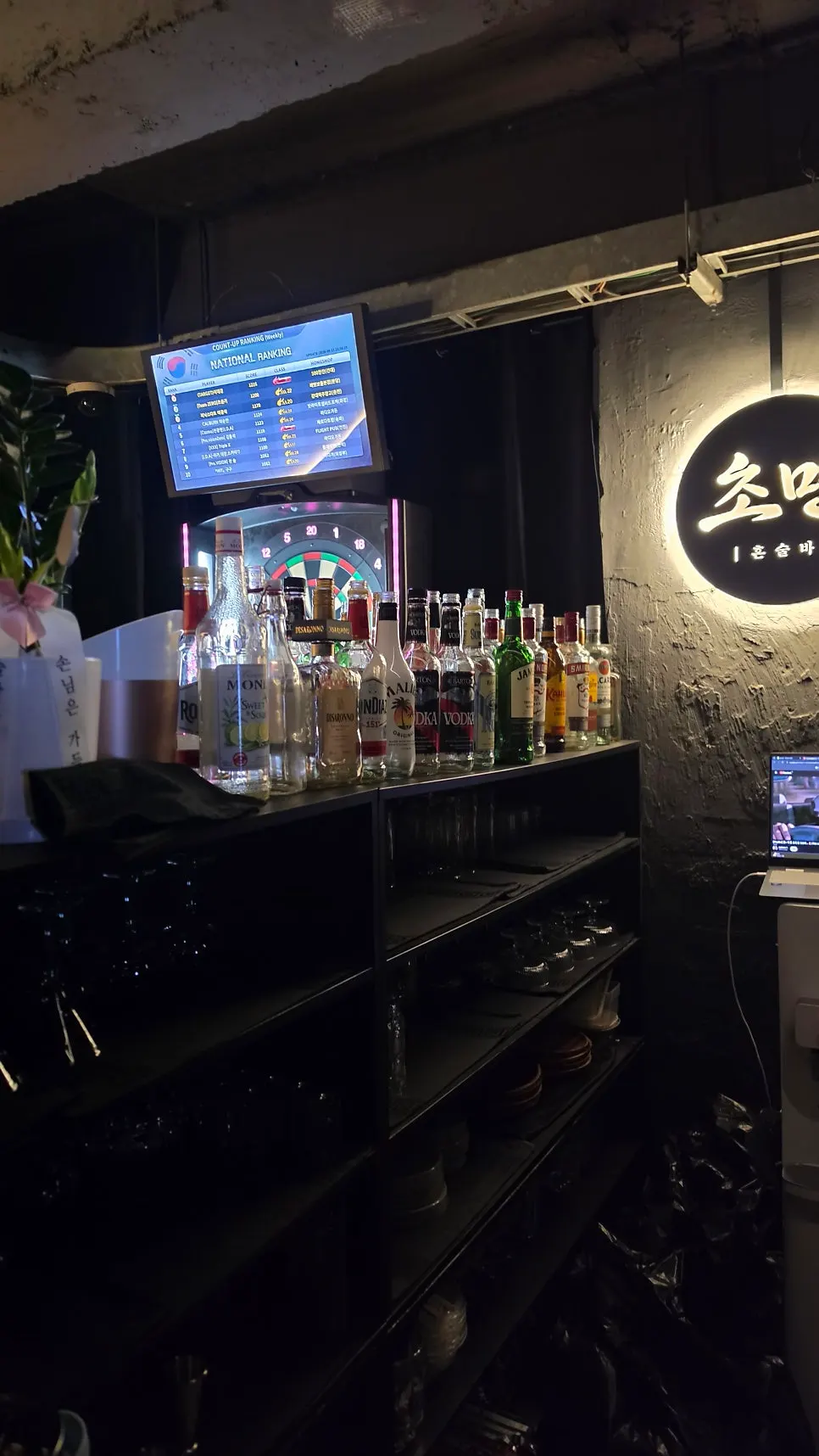 Bar area with displayed liquor bottles and a dart machine