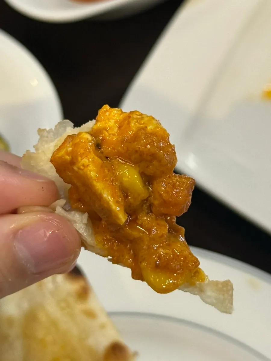 Garlic naan dipped into chicken makhani