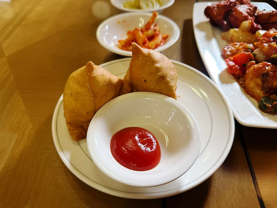 Two samosas served with ketchup