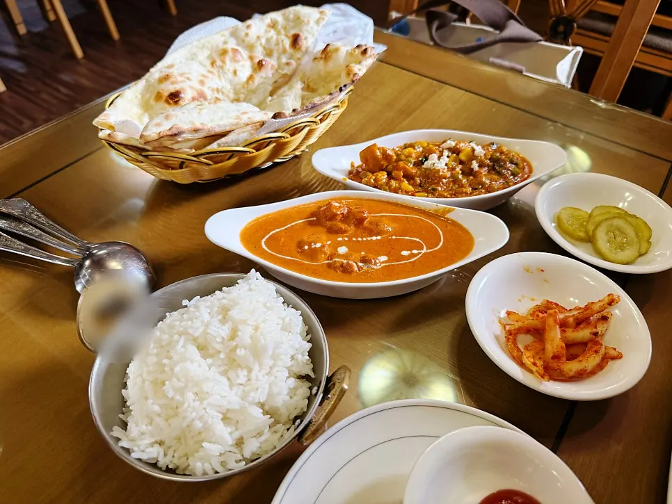 Table set with two curries, rice, and naan