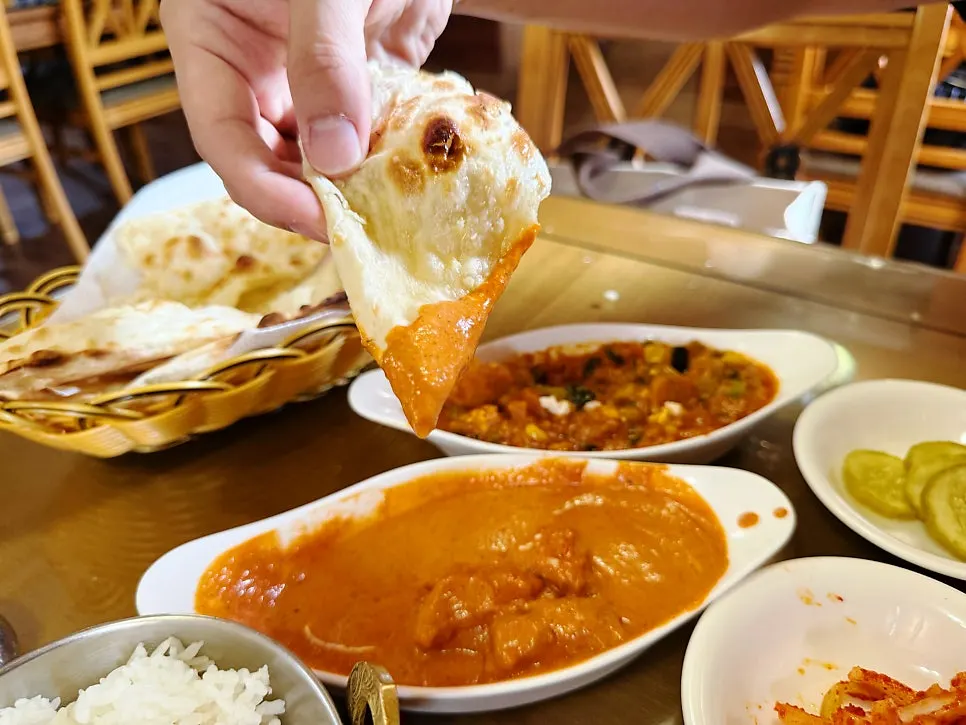Dipping garlic naan into creamy curry