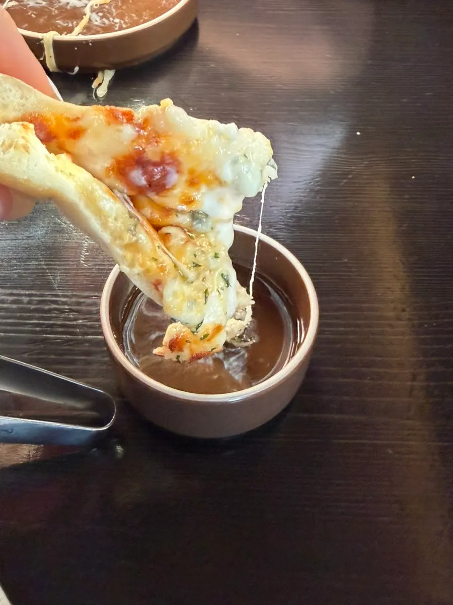 Tay cầm miếng pizza vừa chấm mật ong