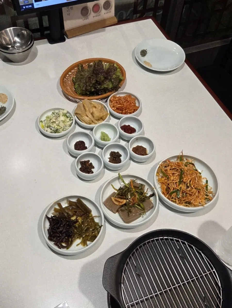 Side dish spread with green onion strips, jelly and pickles