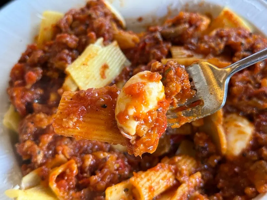 Plate of spicy ragu sauce pasta loaded with meat