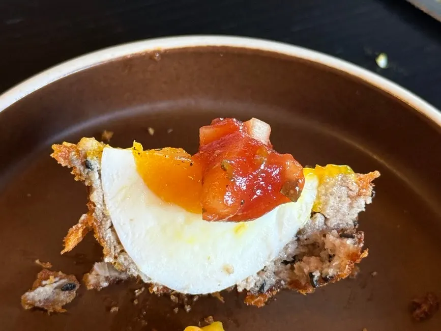 Cross-section of a Scotch egg topped with salsa sauce
