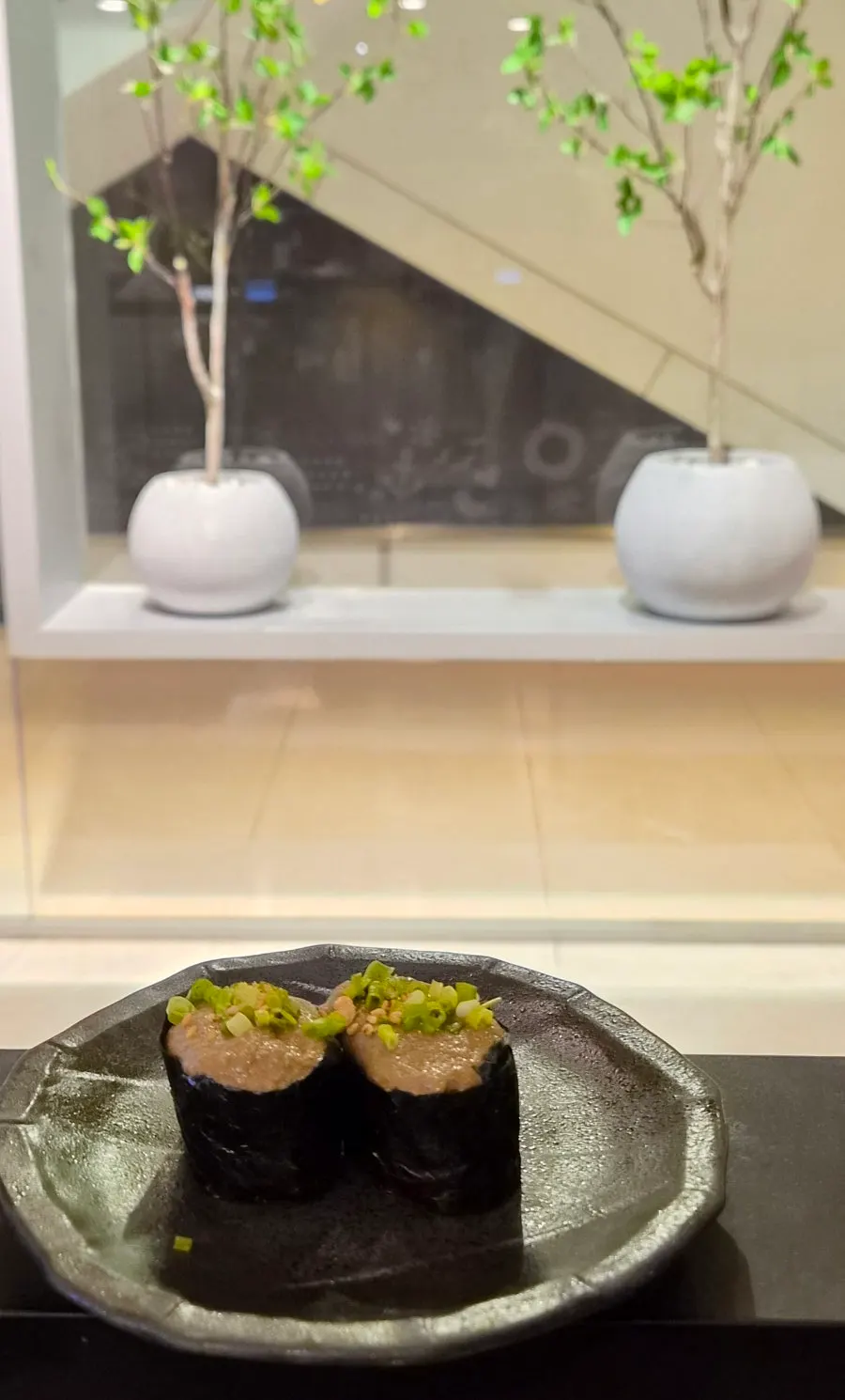 Two kani miso gunkan pieces topped with wasabi