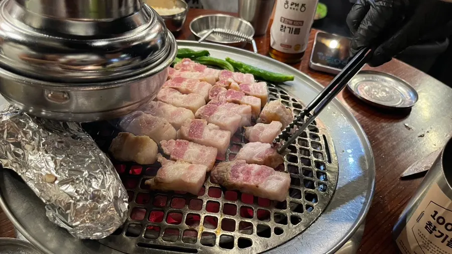 Staff member grilling meat over a charcoal brazier