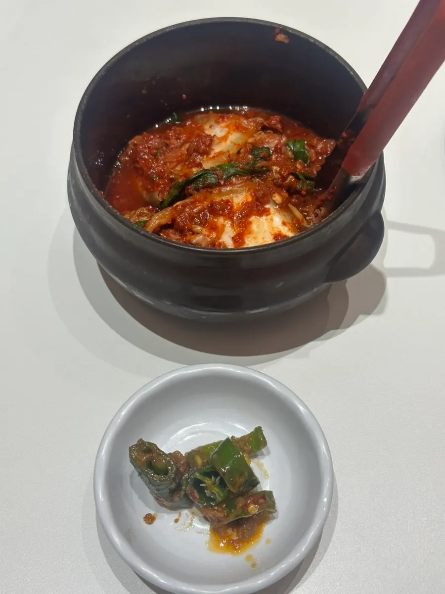 Side dishes of kimchi and cucumber-pepper doenjang mix at Donggok Jemyeon