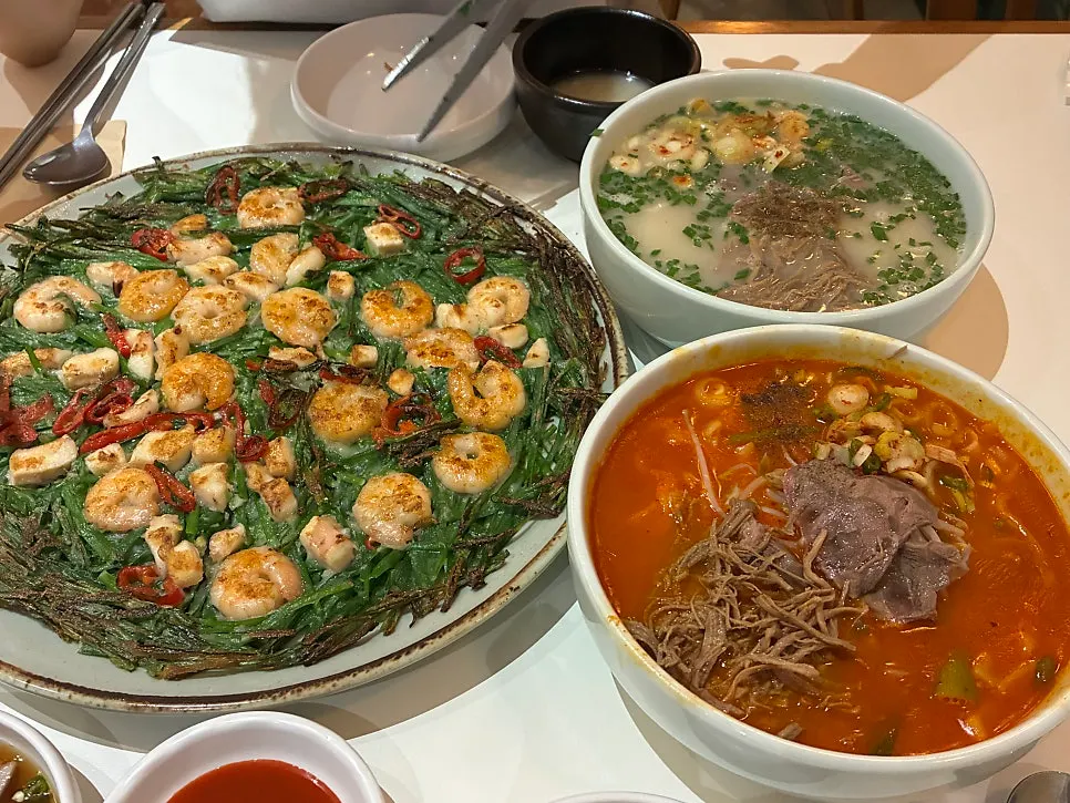 Table with two bowls of kalguksu and makgeolli