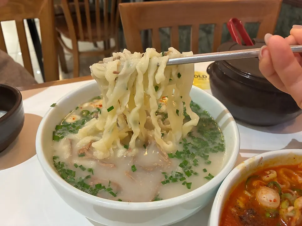 Hanwoo bone-broth kalguksu topped generously with green onion and chives