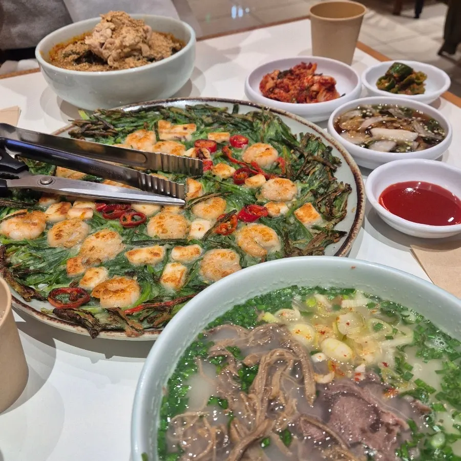 Two bowls of kalguksu and seafood chive pancake laid out together