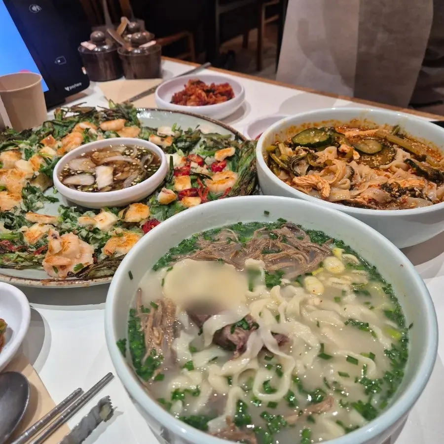Close-up of bone broth kalguksu topped with chives and scallions