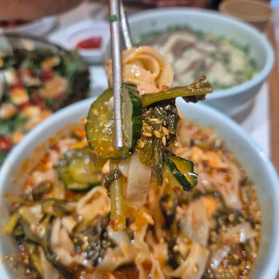 Chogye bibim kalguksu with visible yeolmu and meat toppings