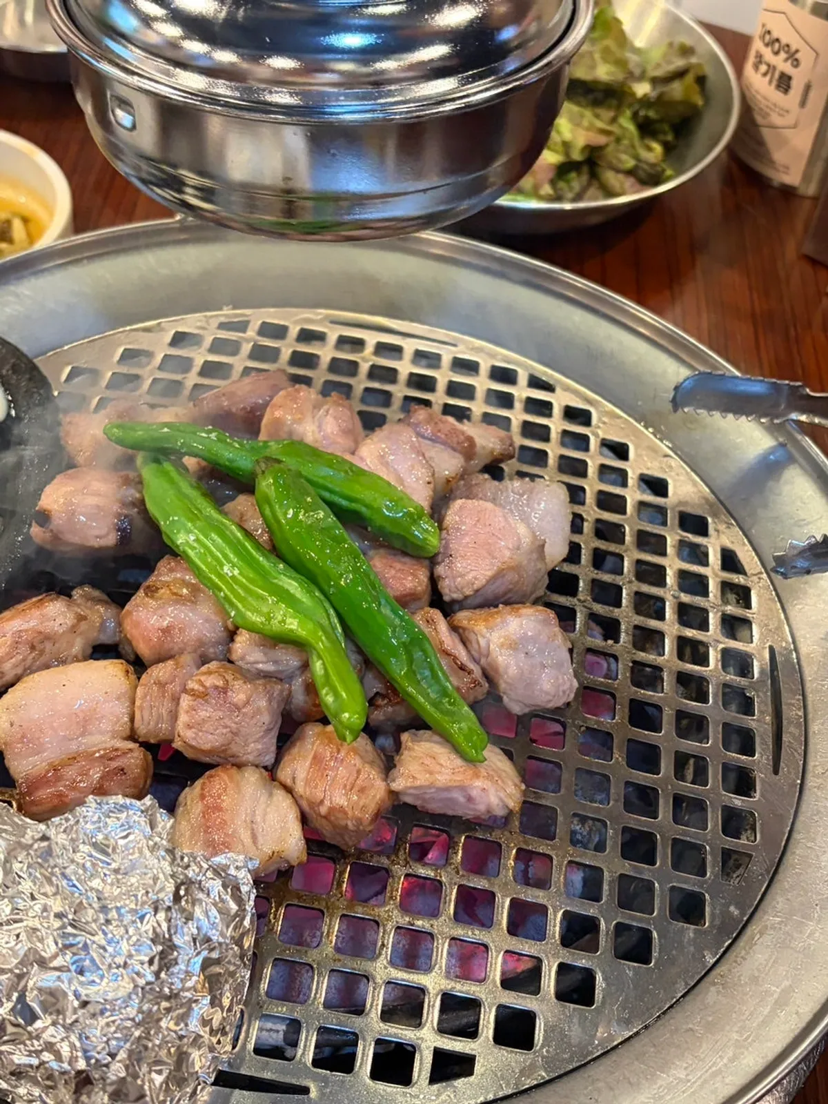 Thick pork neck grilling with visible smoke